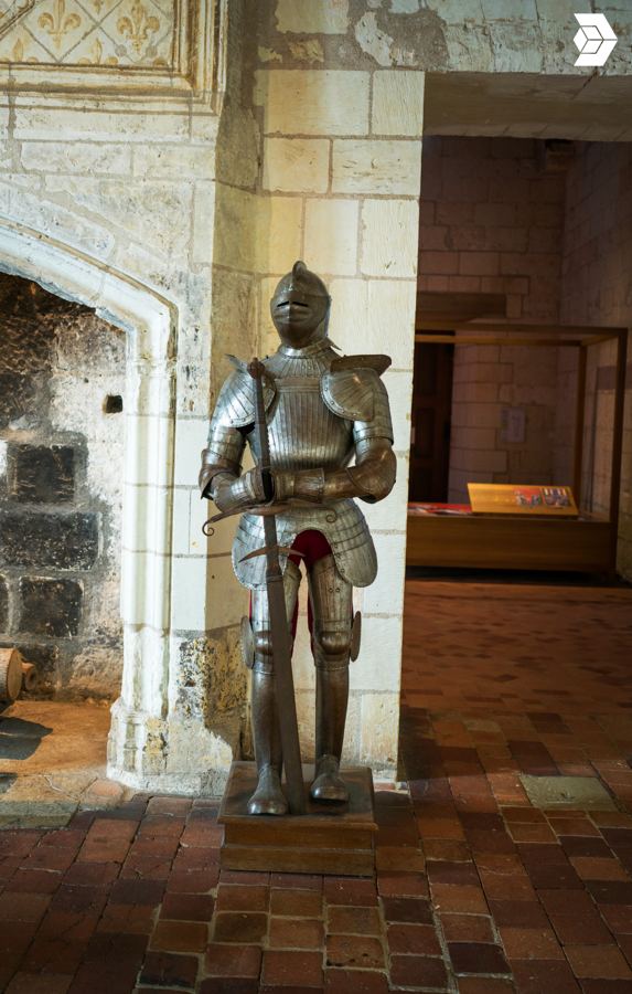 Armure exposée devant une cheminée du logis